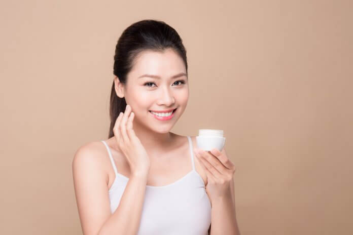 Skincare. Beautiful asian woman show moisturizer or lotion product. Top 5 odżywczych kremów do skóry suchej i mieszanej